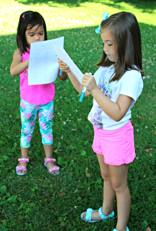 2 kids holding paper and markers with Back yard Scavenger Hunt printable