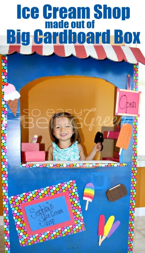little girl standing inside big cardboard box made into a a playhouse