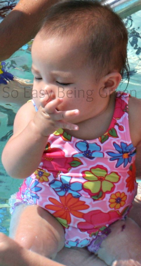 Baby sitting in pool with bathing suit and cloth swim diaper