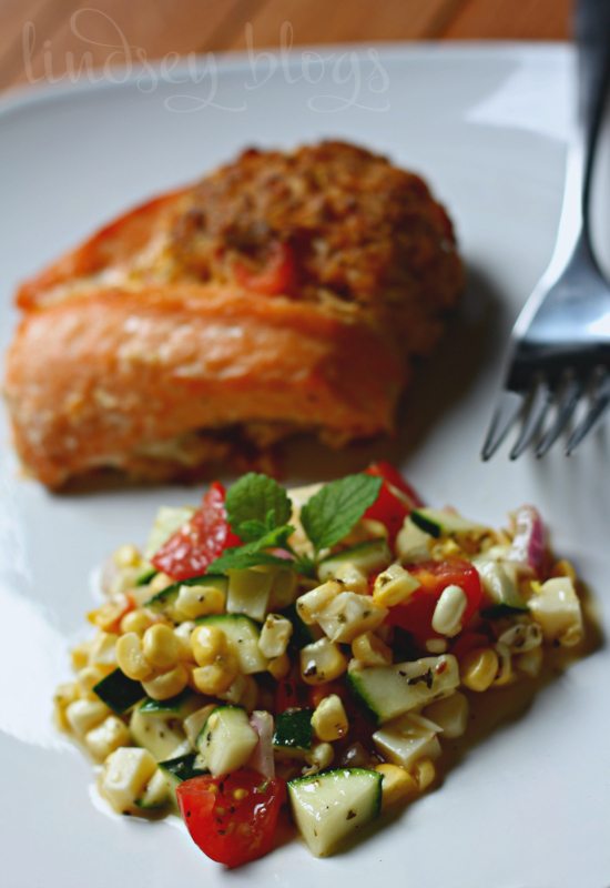 Fresh Zucchini Corn Salad with salmon on white plate with fork