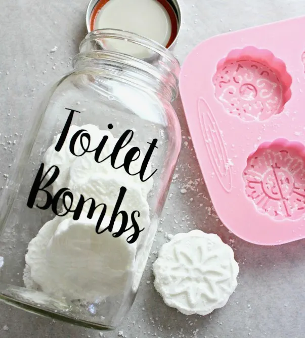 white cleaner tablet beside pink silicone mold and jar with toilet bombs in text