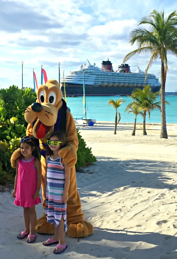 girls and pluto on castaway cay with disney magic in back