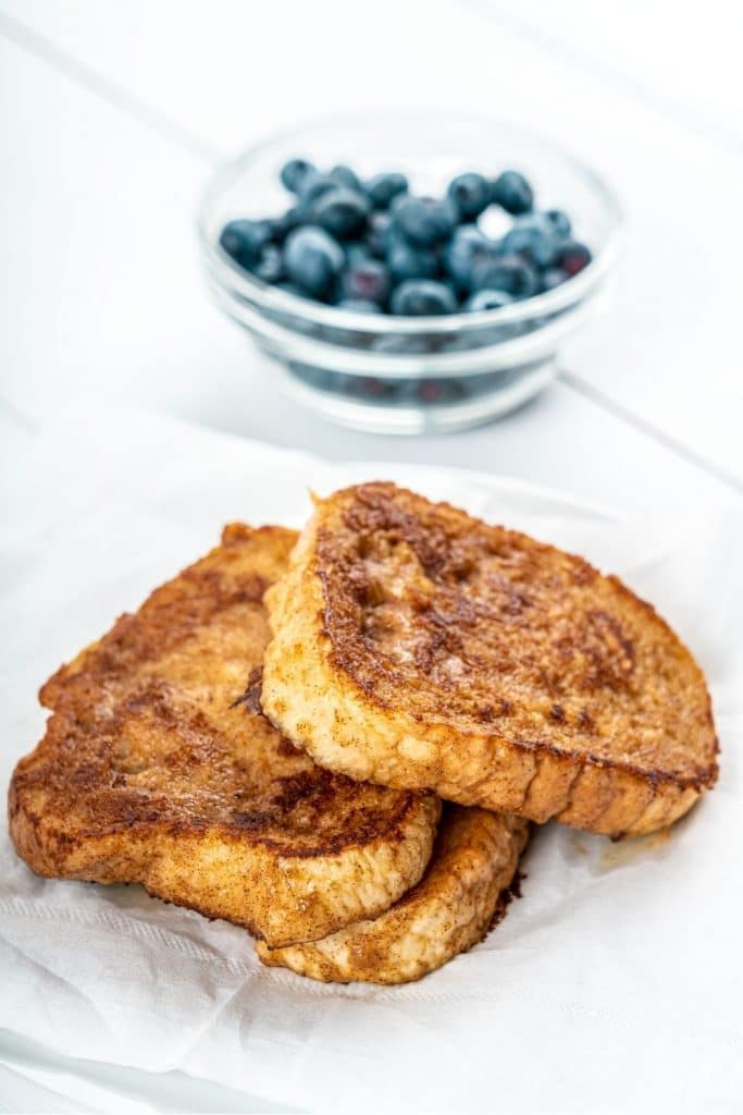 french toast on white plate with blueberries in dish 