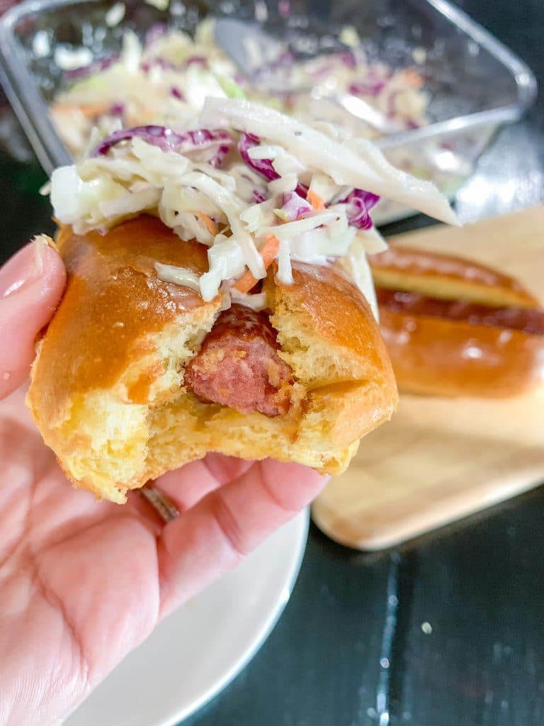 hand holding hot dog with coleslaw
