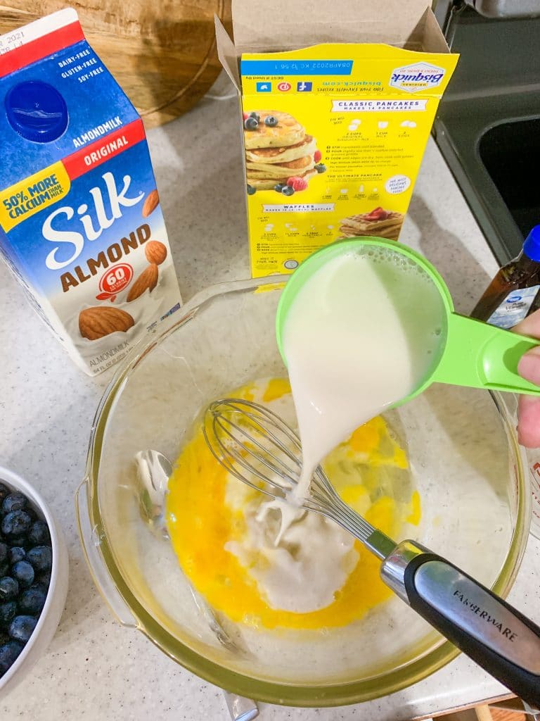 pouring almond milk into pancake mix ingredients
