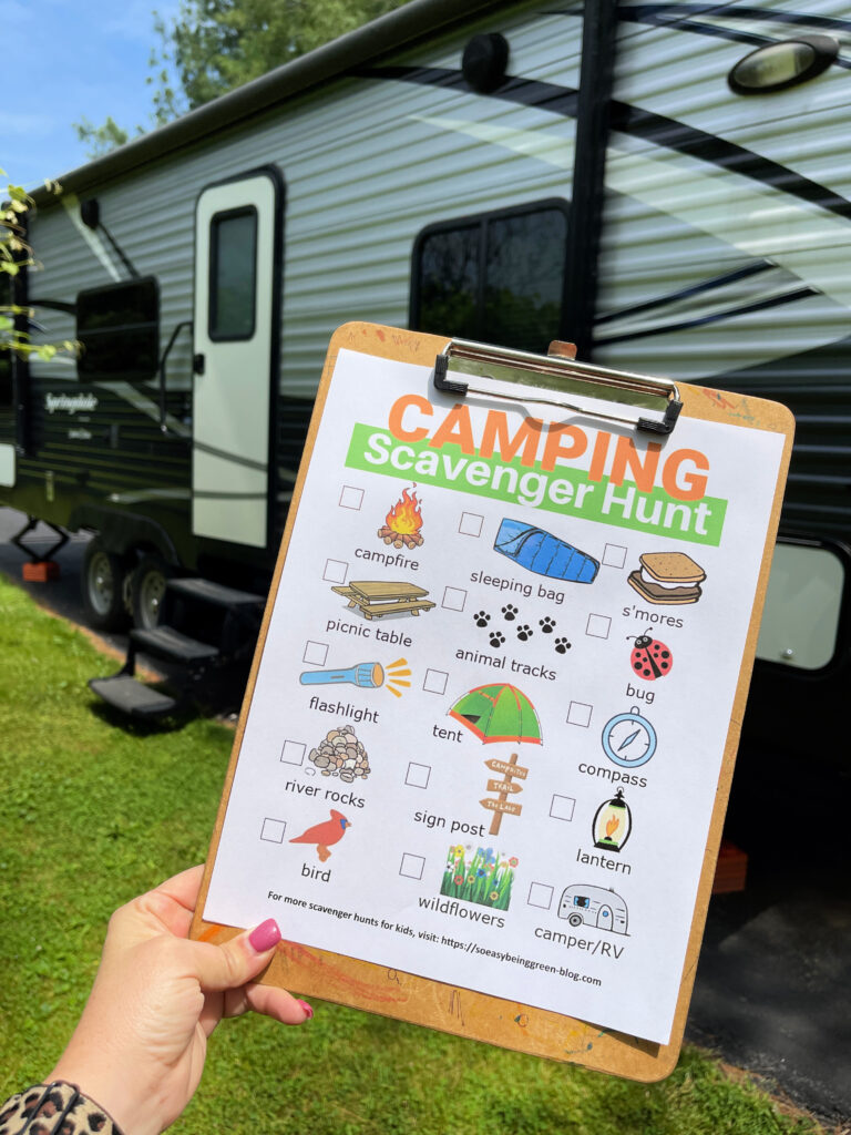 camping scavenger hunt printable on clipboard beside camper rv