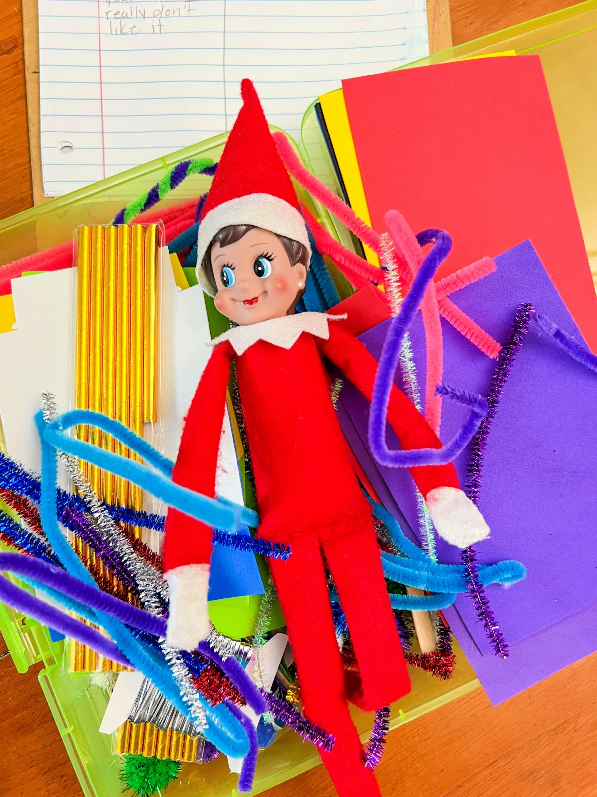 elf on the shelf laying on top of craft supplies